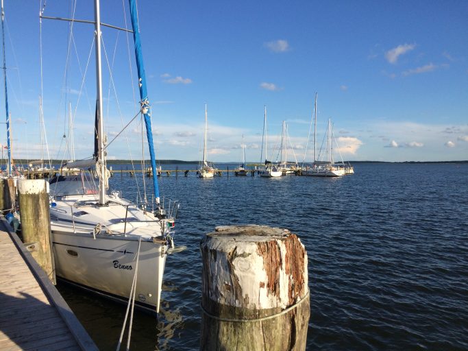 Segelboote am Hafen, ruhiges Wasser und blauer Himmel.