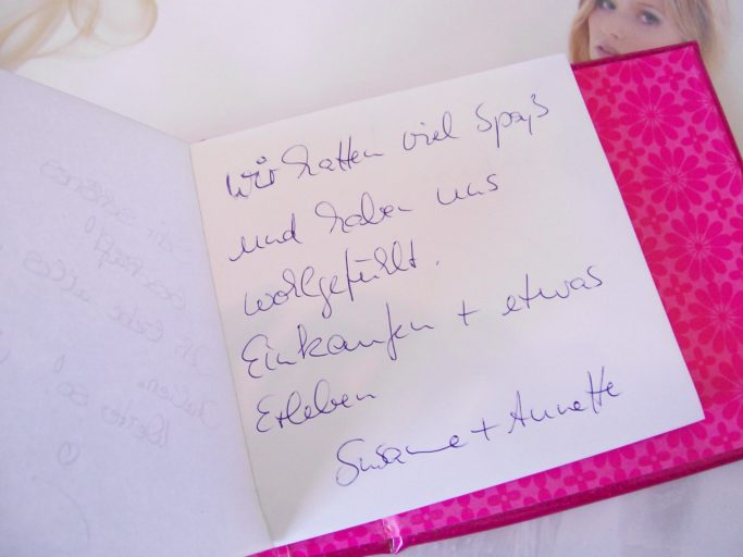 Handschriftliche Notizen in einem offenen Notizbuch auf pinkem Hintergrund.