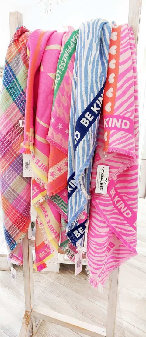 Fünf bunte Tücher in verschiedenen Mustern hängen auf einem Ständer.