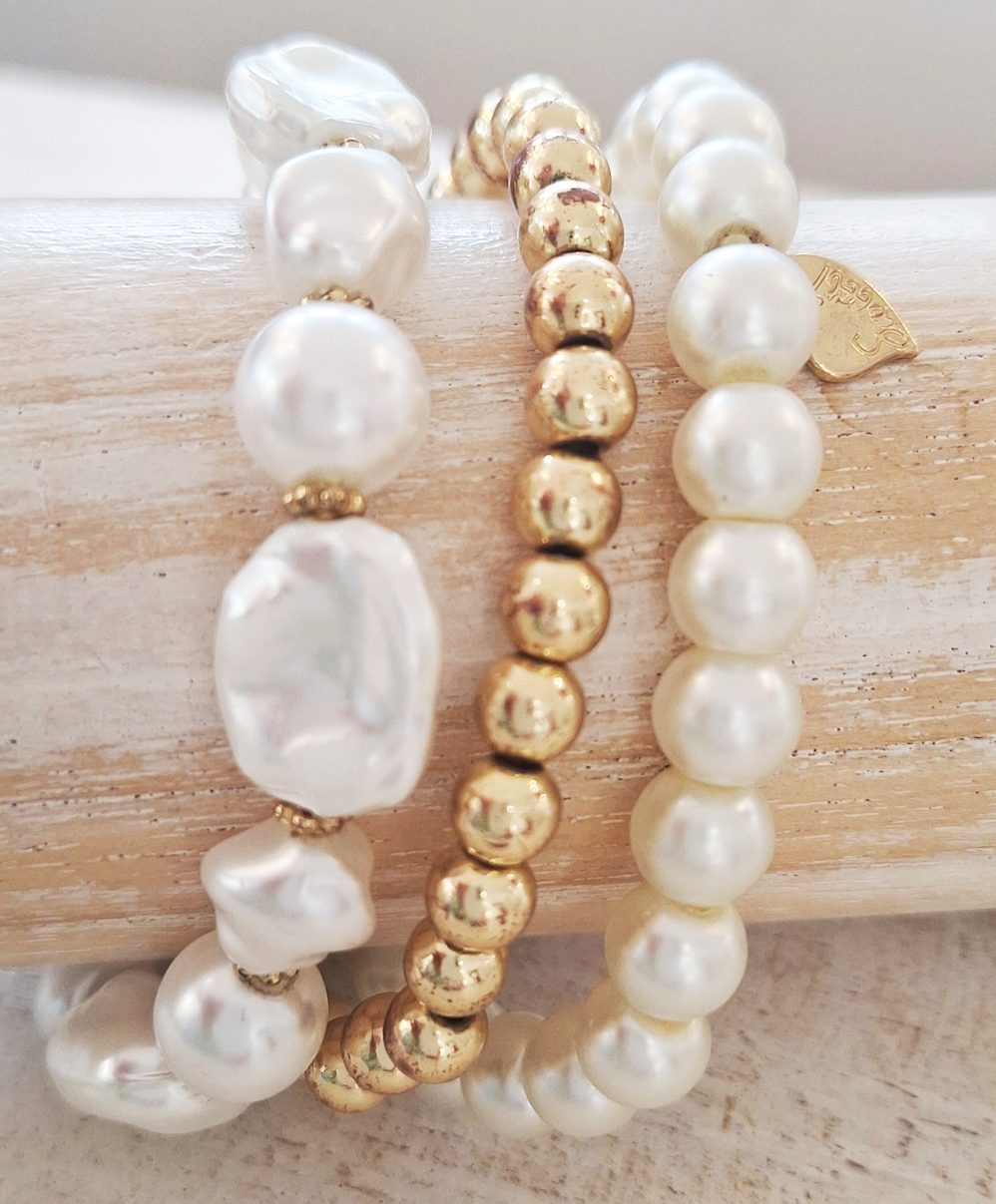 Stylische Armbänder aus Perlen und goldfarbenen Elementen auf einem hellen Hintergrund.
