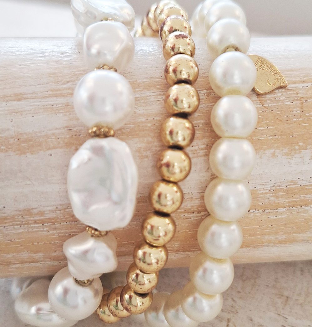 Modegeschäft & Boutique in Oldenburg Stylische Armbänder aus Perlen und goldfarbenen Elementen auf einem hellen Hintergrund.