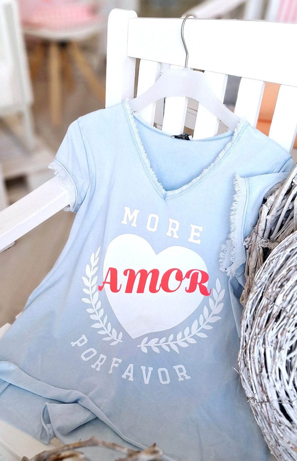 Hellblaues T-Shirt mit Aufschrift "More Amor Por Favor" in roter Schrift.