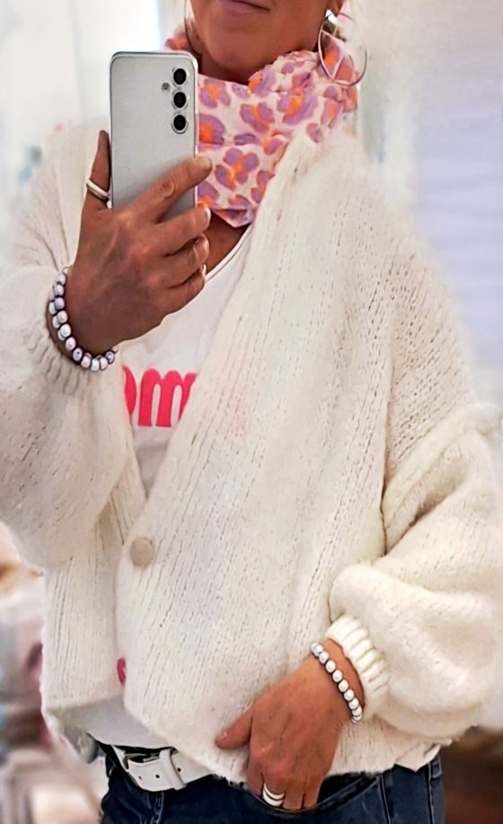 Person mit weißer Jacke, pinkem Shirt und gemustertem Schal