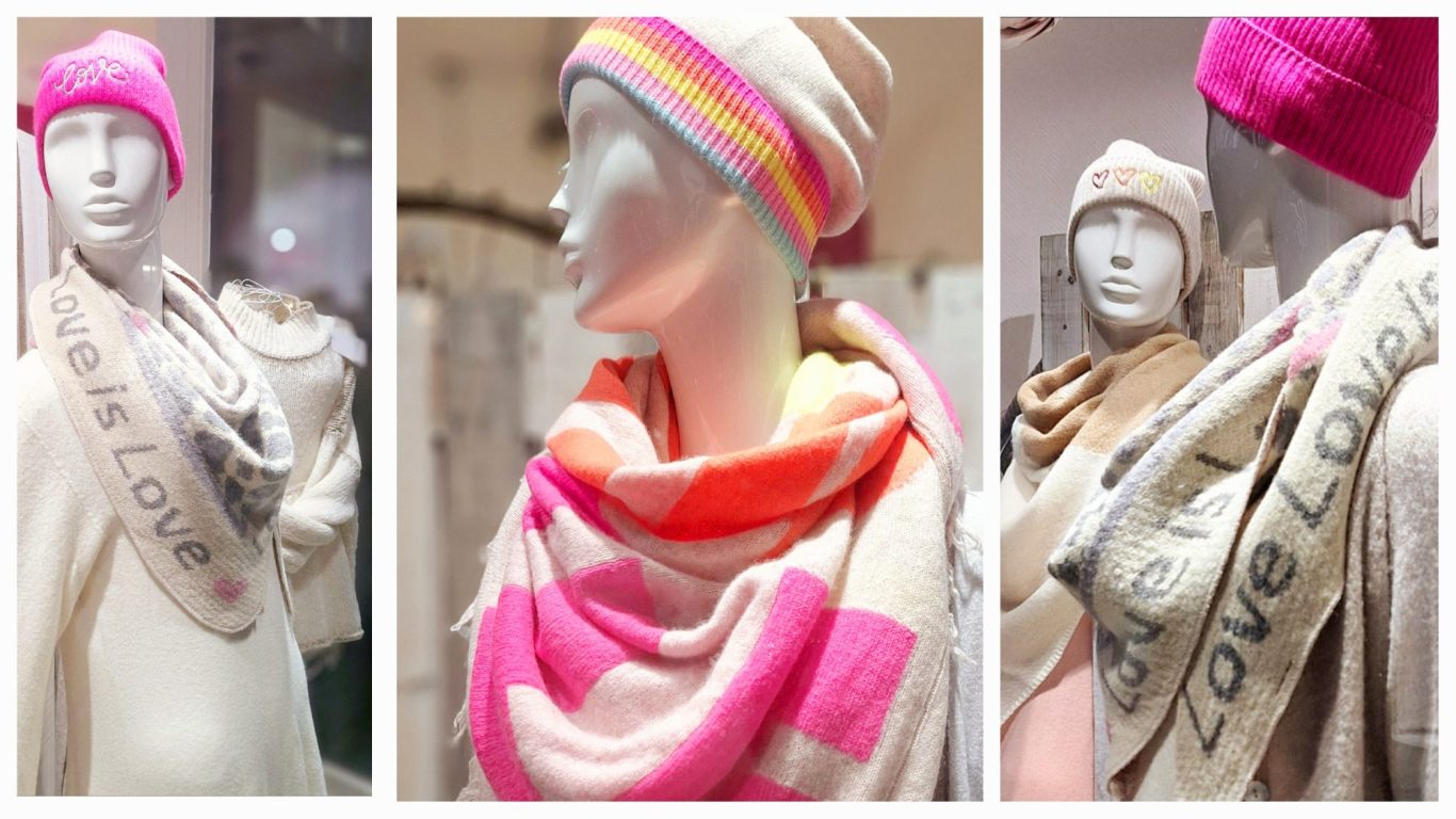 Drei Schaufensterpuppen tragen Strickkleider,  bunte Schals und Mützen mit Love-Motiven.