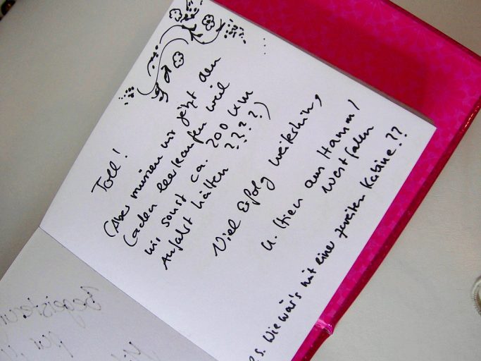 Eine handgeschriebene Notiz mit geschwungener Schrift auf einem bunten Papier.
