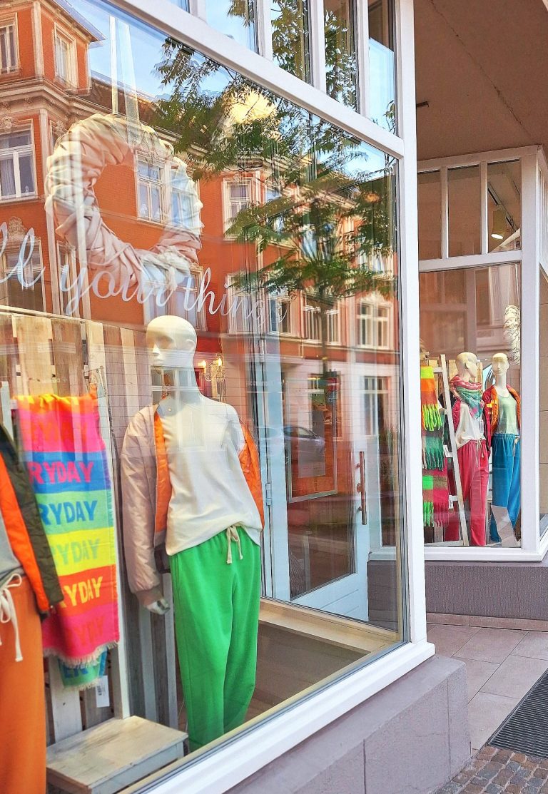 Schaufenster mit bunten Kleidungsstücken und Schaufensterpuppen.