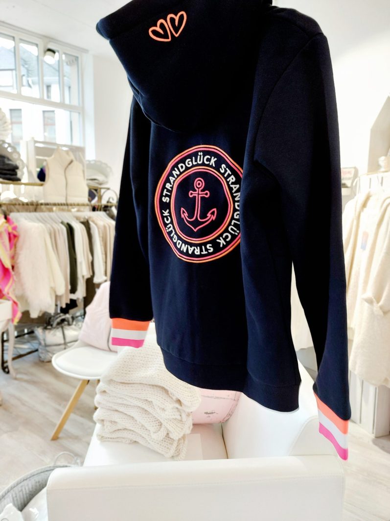 Dunkelblaues Sweatshirt mit rosa Anker-Logo und bunten Bündchen.