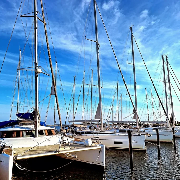 Segelboote im Hafen bei klarem Himmel und ruhigem Wasser.