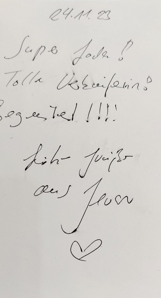 Handgeschriebene Notiz mit freundlichen Botschaften und einem Herz-Symbol.