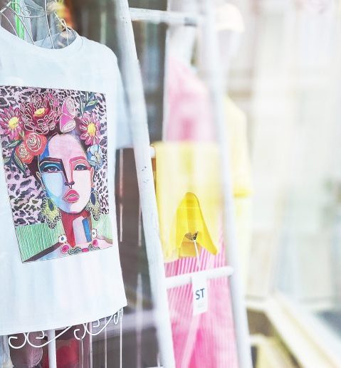 Weißes T-Shirt mit farbenfrohem, künstlerischem Frauenporträt und Blumenmotiven.