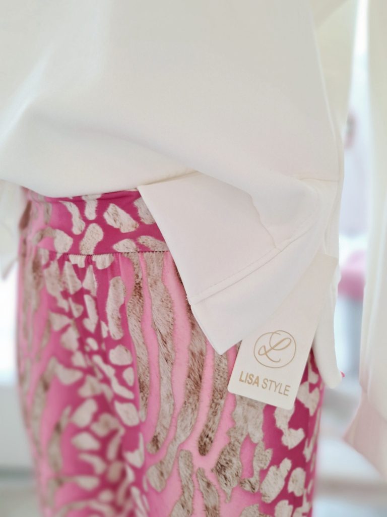 Detailaufnahme von einem weißen Oberteil und einer pink-musternden Hose.