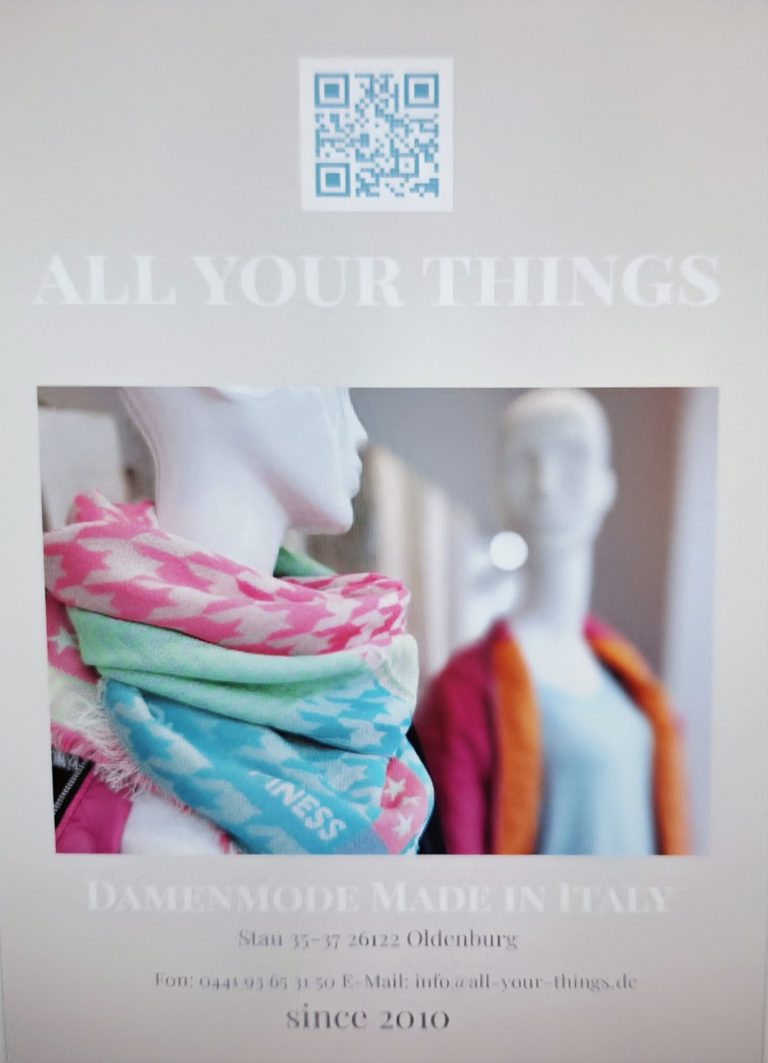 Ein Flyer zeigt Schaufensterpuppen mit farbigem Schal und Pullover in einem eleganten Geschäft.